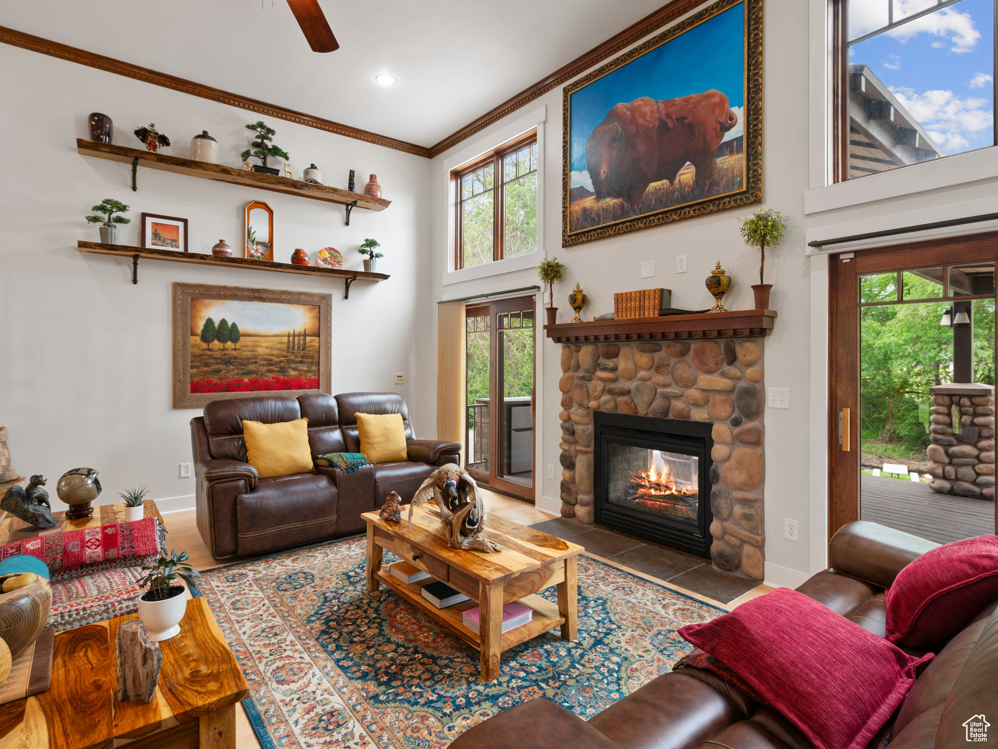 Living room with a towering ceiling, ceiling fan, a fireplace, and crown molding