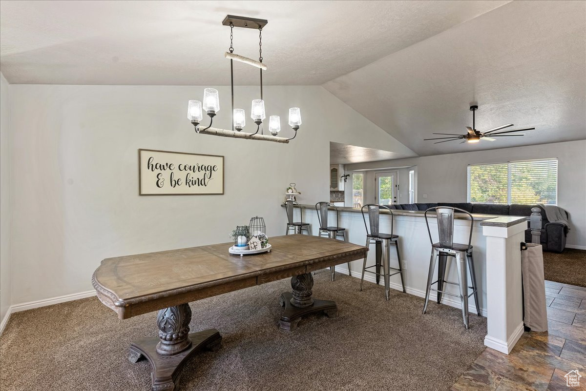 Carpeted dining room featuring french doors, ceiling fan with notable chandelier, and lofted ceiling