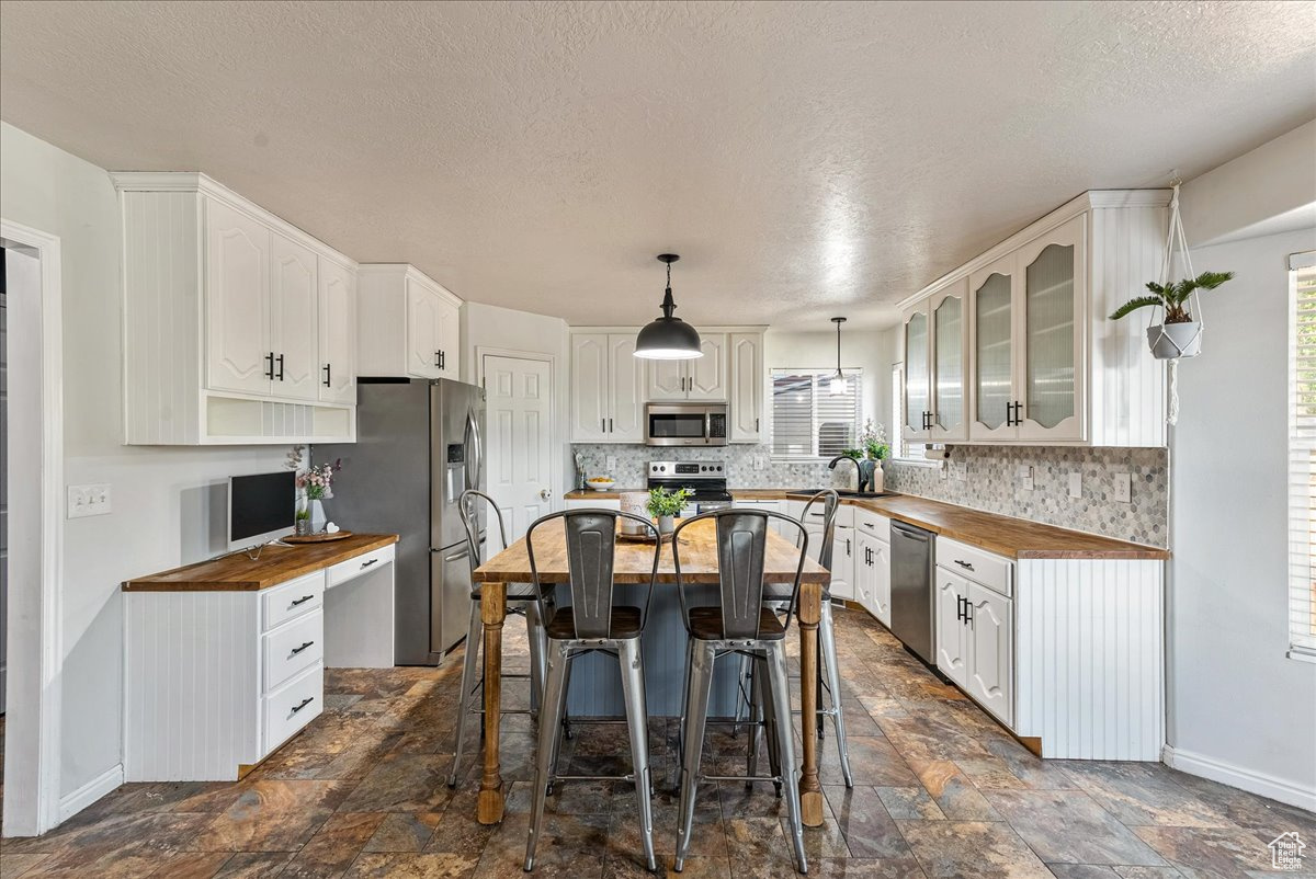 Kitchen featuring white cabinets, butcher block countertops, and appliances with stainless steel finishes