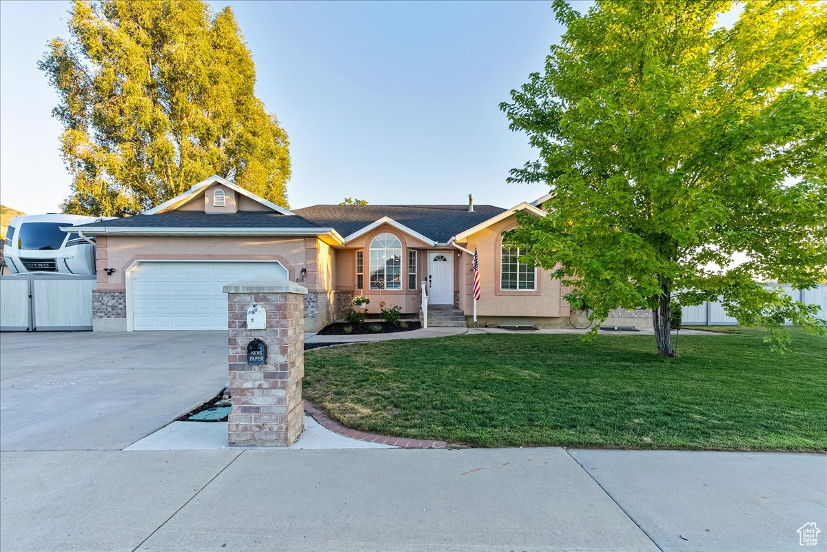 Ranch-style house featuring a front lawn and a garage