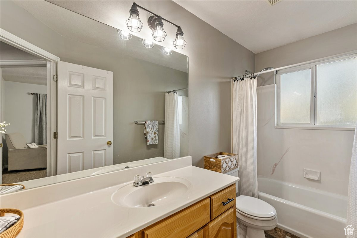 Full bathroom featuring vanity, toilet, and shower / bath combo with shower curtain