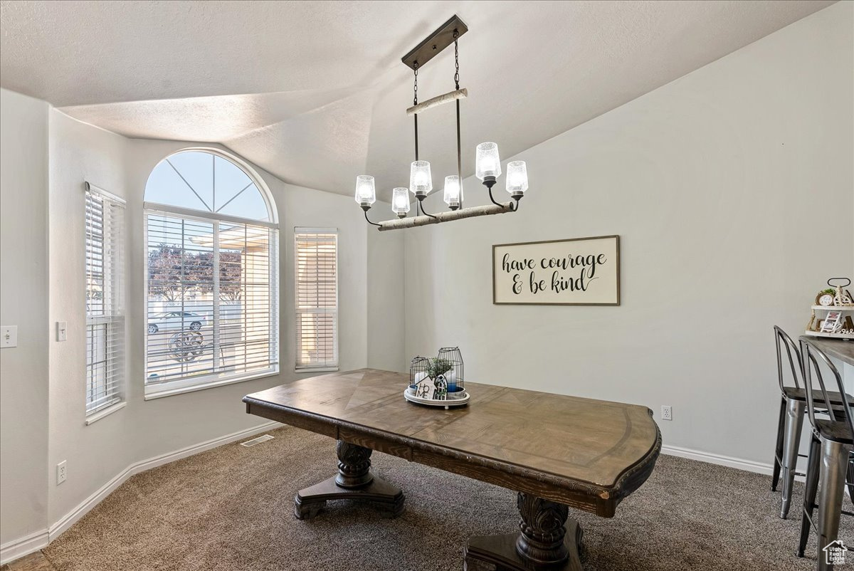 Dining room featuring a chandelier, carpet floors, and vaulted ceiling