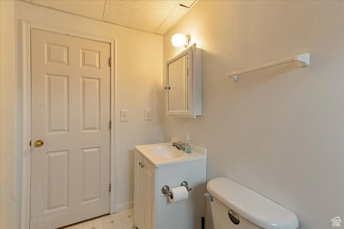 Bathroom with tile flooring, vanity, toilet, and a drop ceiling