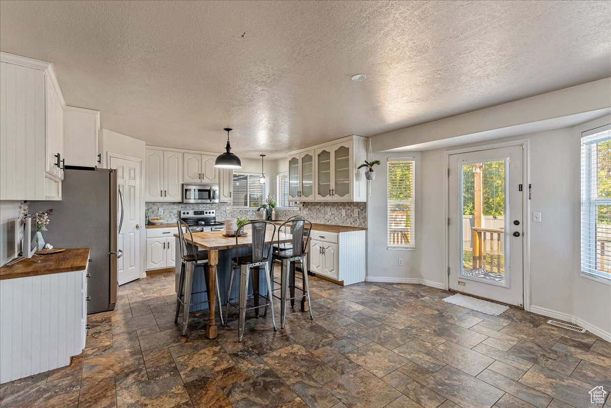 Kitchen with a wealth of natural light, wooden counters, and appliances with stainless steel finishes