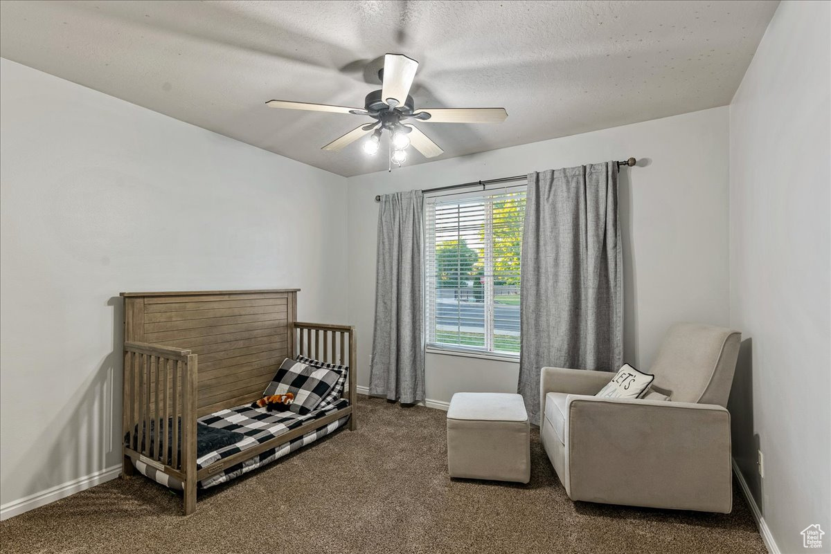 Bedroom with a textured ceiling, ceiling fan, and carpet floors