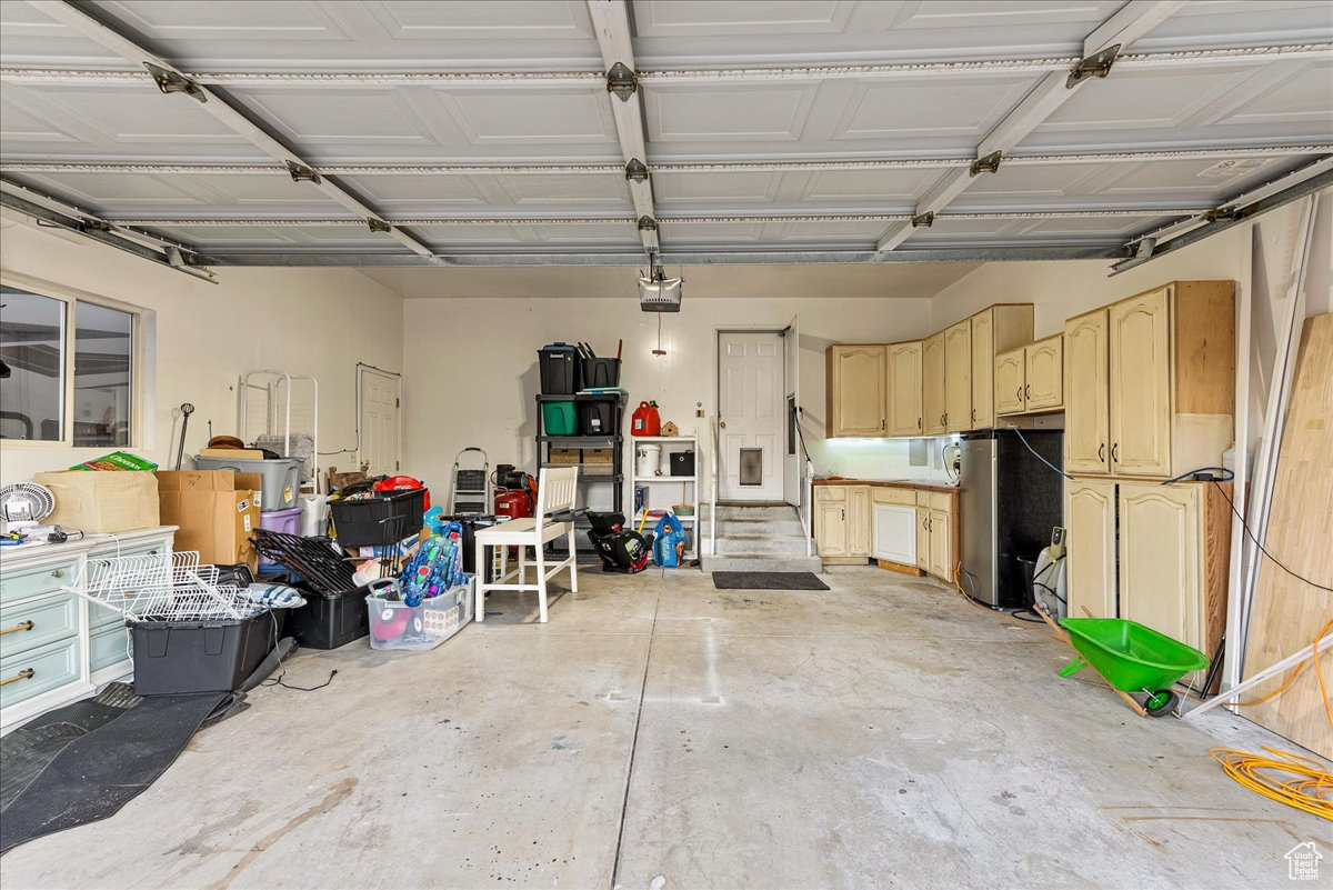 Garage featuring a garage door opener and stainless steel refrigerator