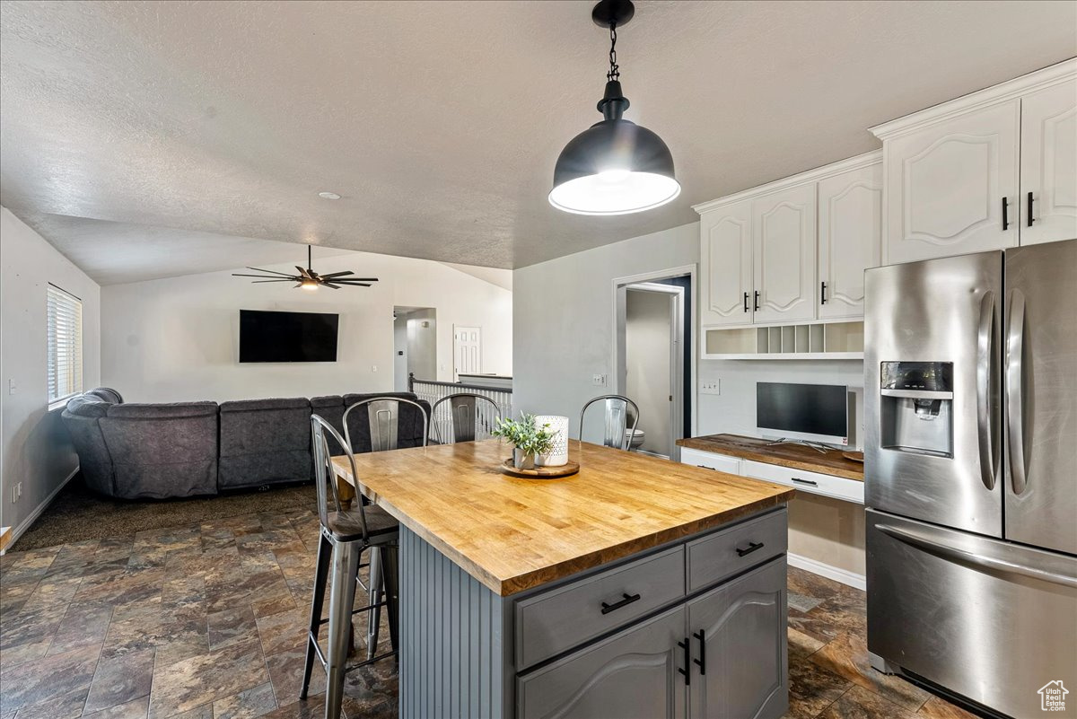 Kitchen with white cabinetry, stainless steel fridge with ice dispenser, wood counters, a kitchen island, and gray cabinetry