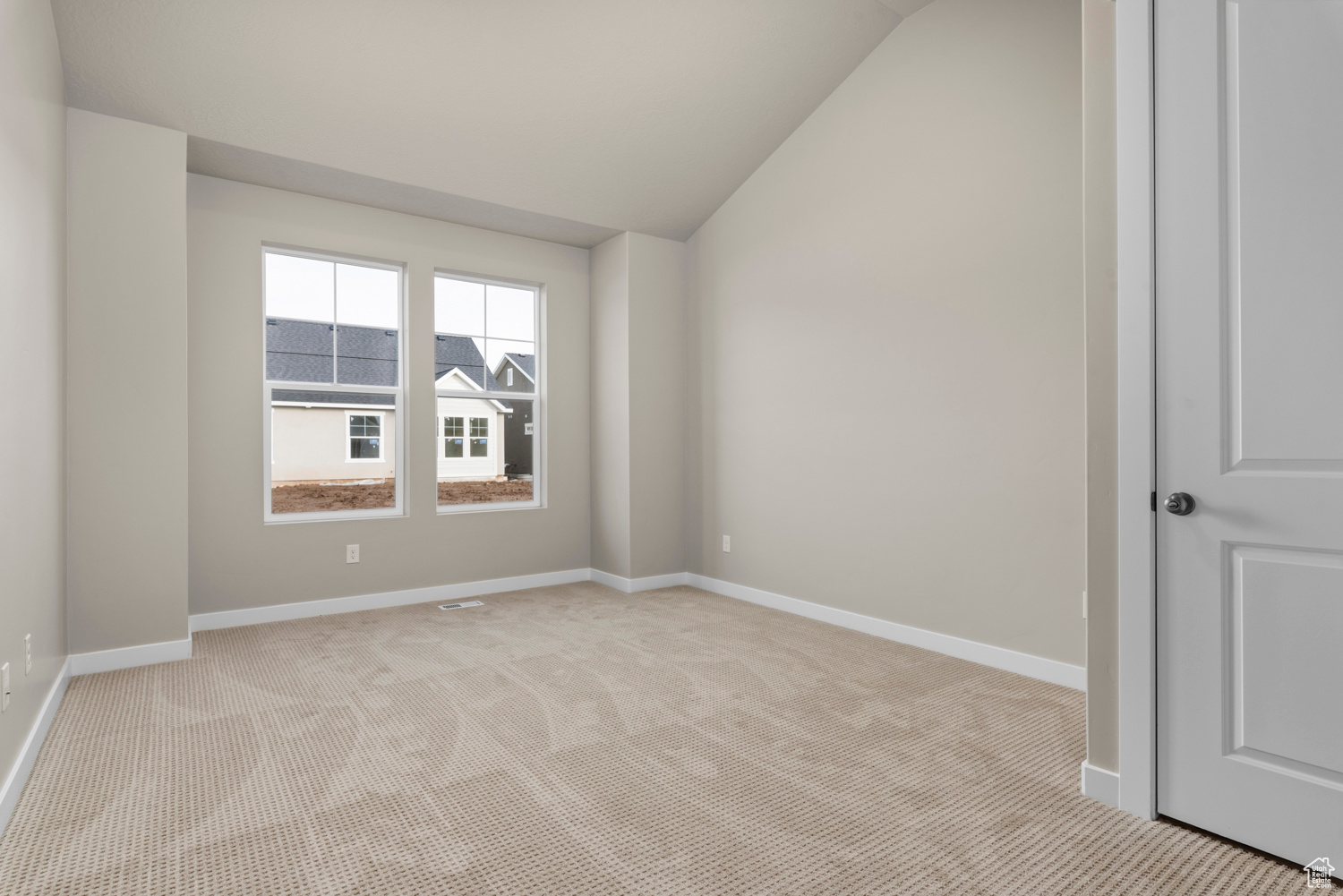 Carpeted empty room featuring lofted ceiling