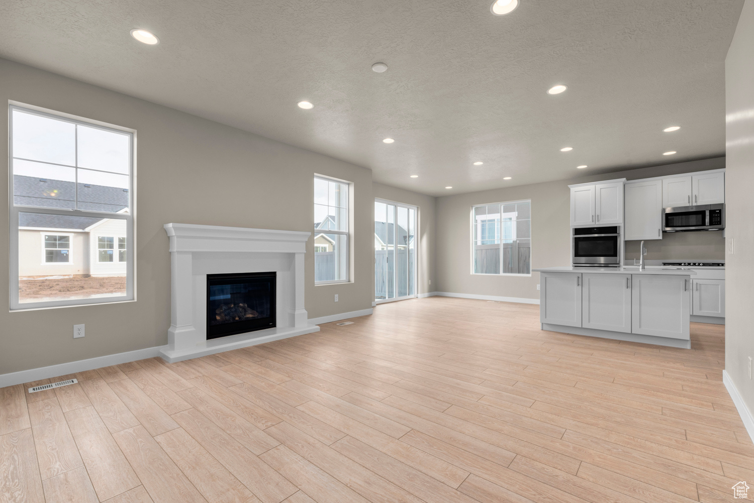 Unfurnished living room featuring a wealth of natural light, sink, and light wood-type flooring