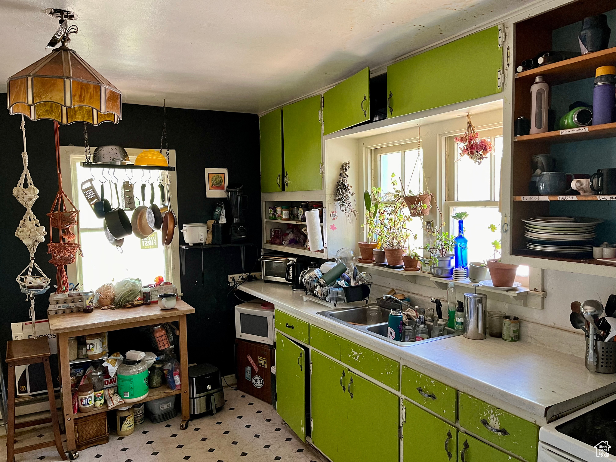 Kitchen featuring sink, green cabinets, and pendant lighting