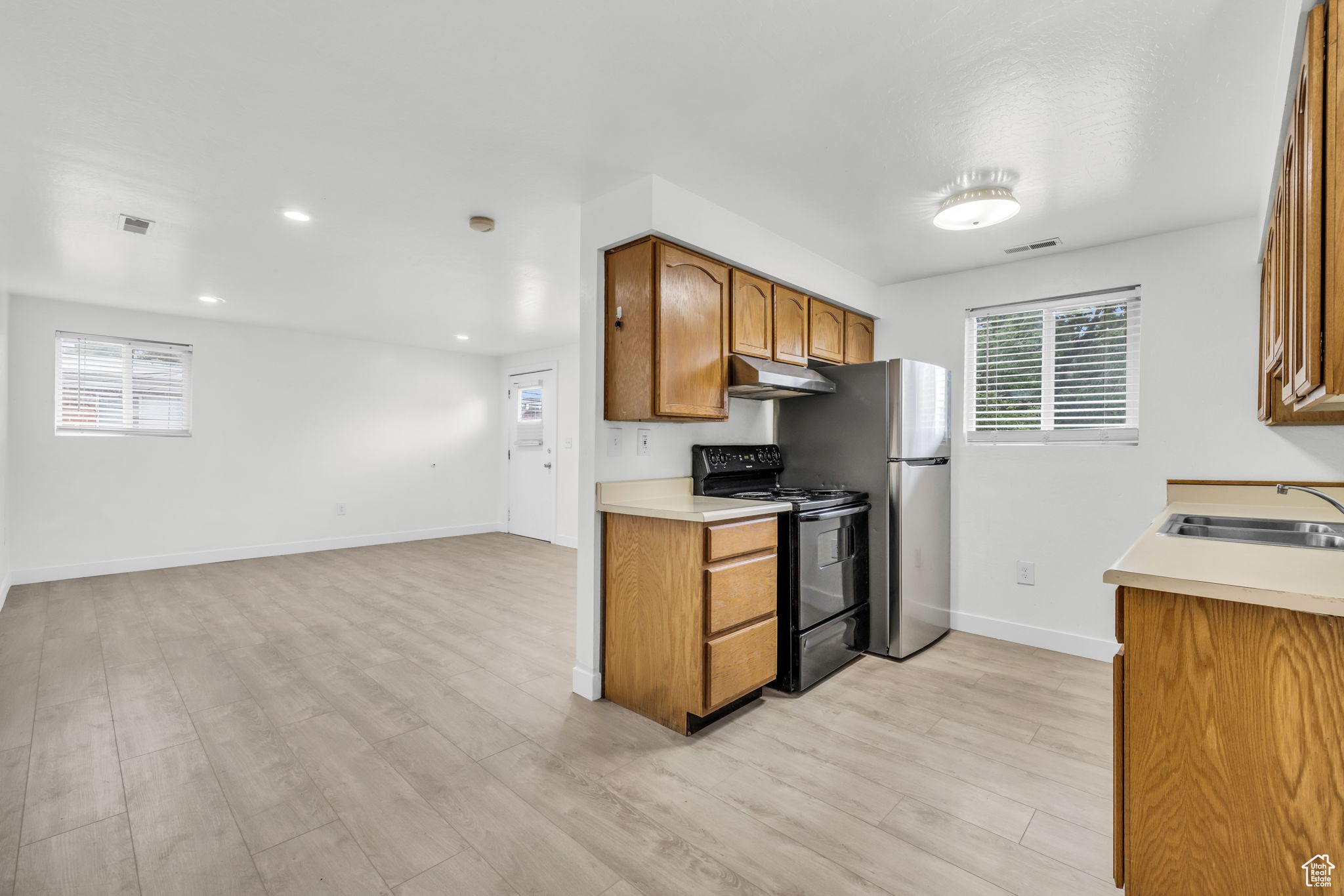 Kitchen with a healthy amount of sunlight, sink, range with electric cooktop, and light wood-type flooring