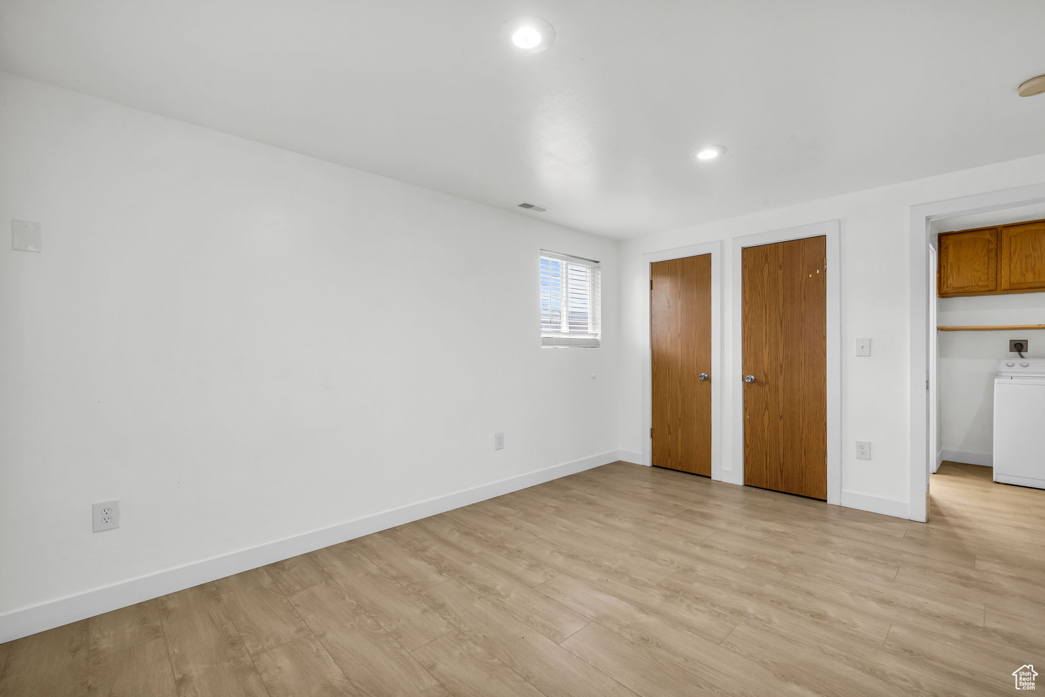 Unfurnished bedroom with two closets, light hardwood / wood-style flooring, and washer / clothes dryer