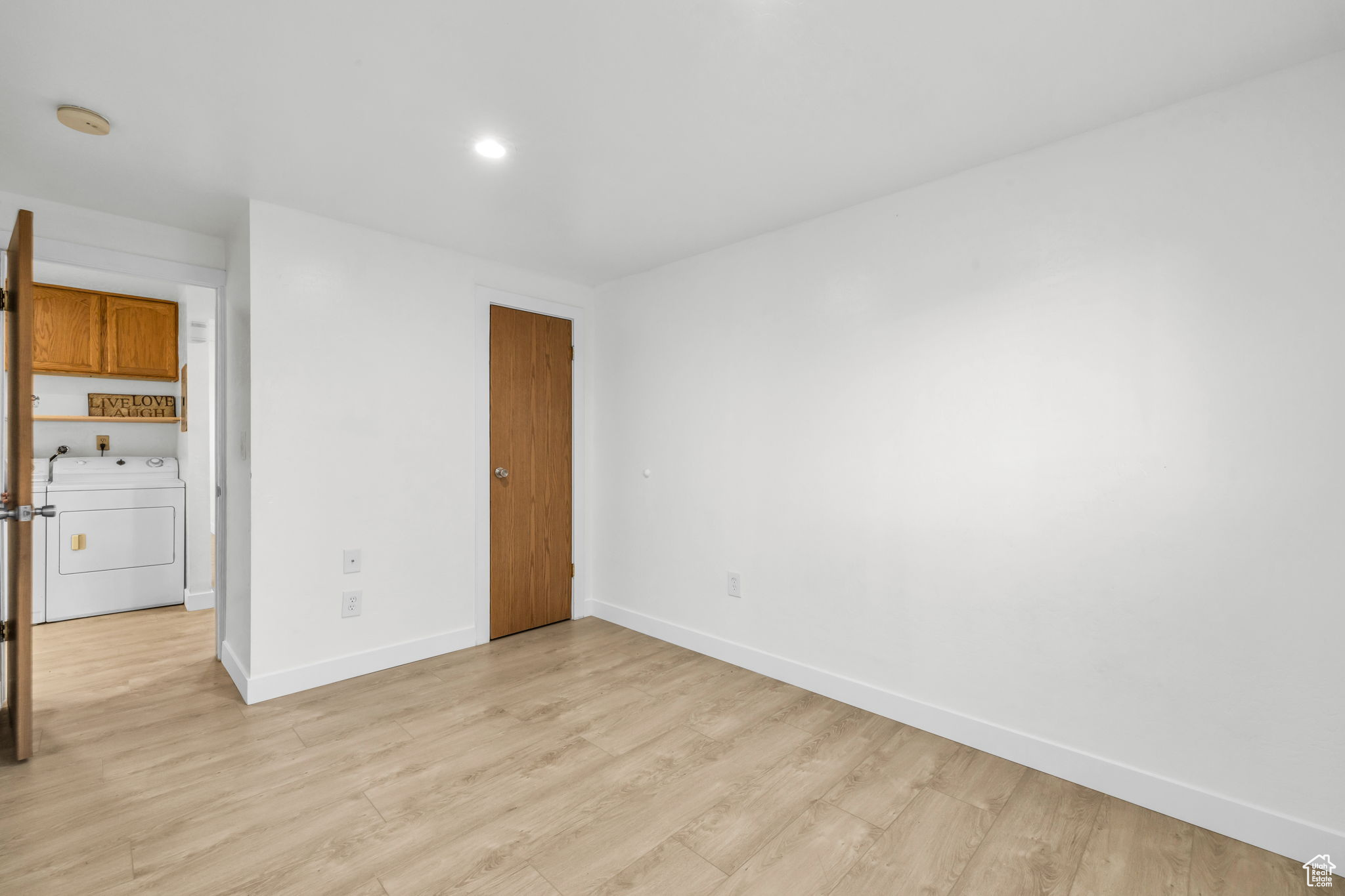 Spare room with washer / dryer and light hardwood / wood-style flooring