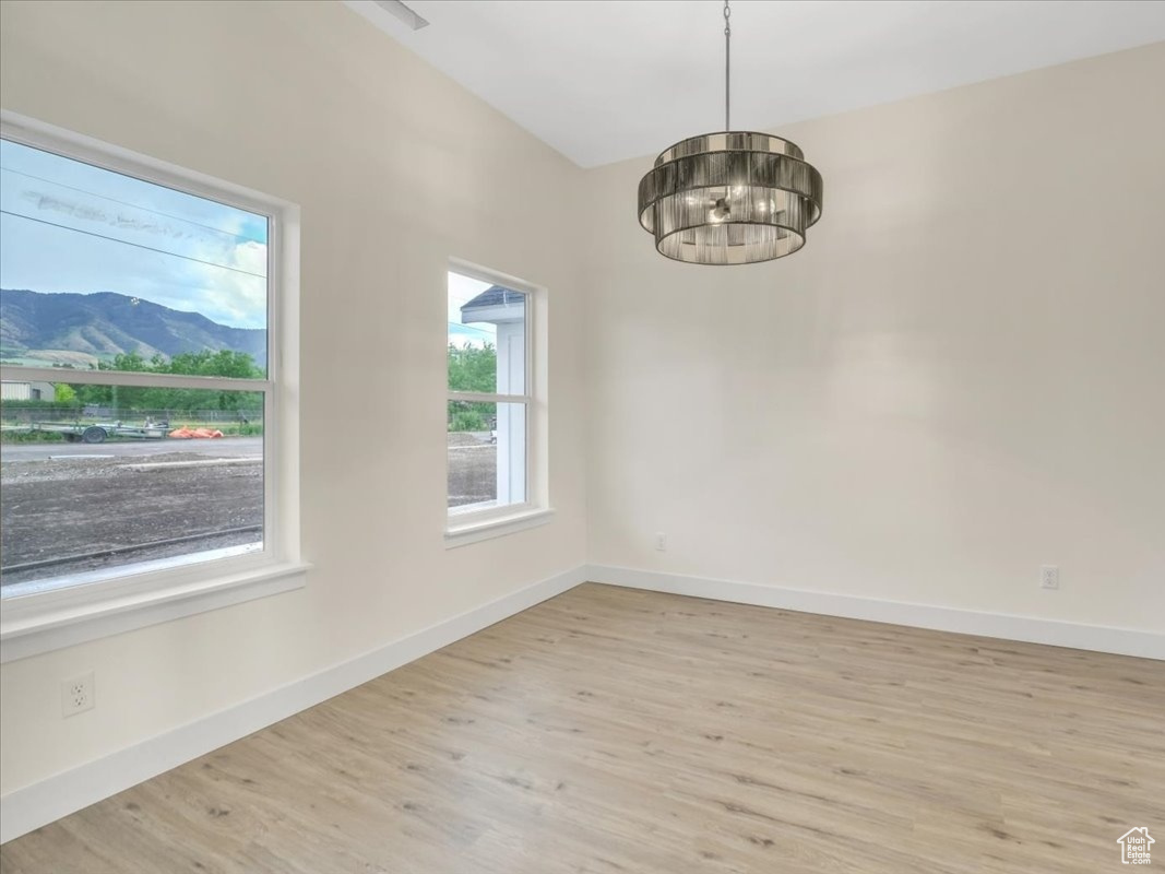 Unfurnished room featuring a notable chandelier, a mountain view, and light wood-type flooring