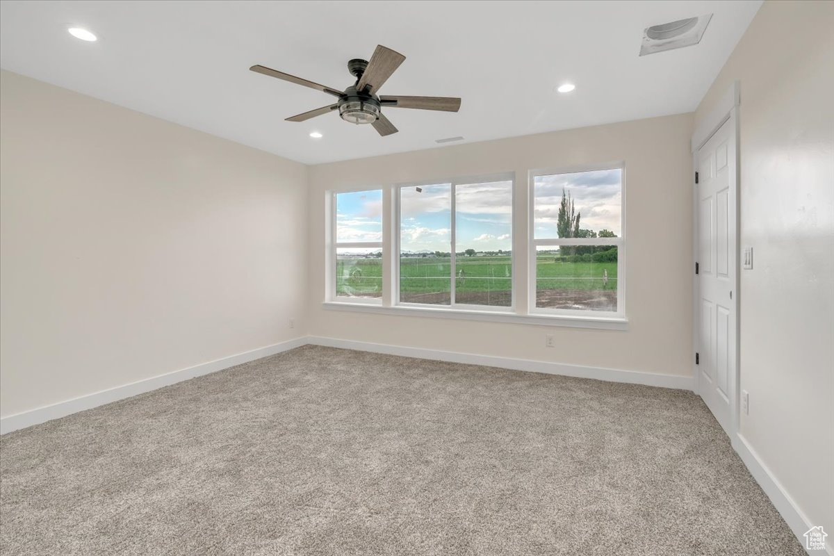 Spare room featuring carpet and ceiling fan