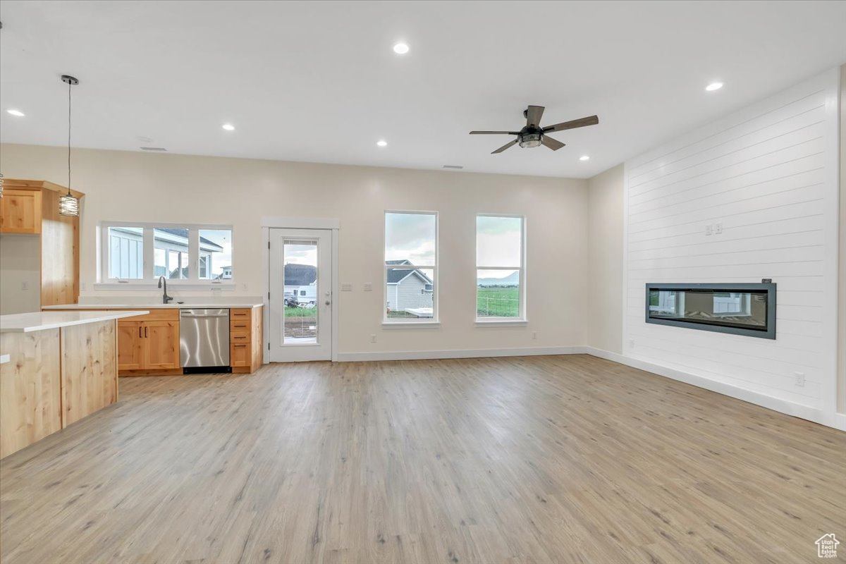 Unfurnished living room with light hardwood / wood-style floors, a fireplace, and a healthy amount of sunlight