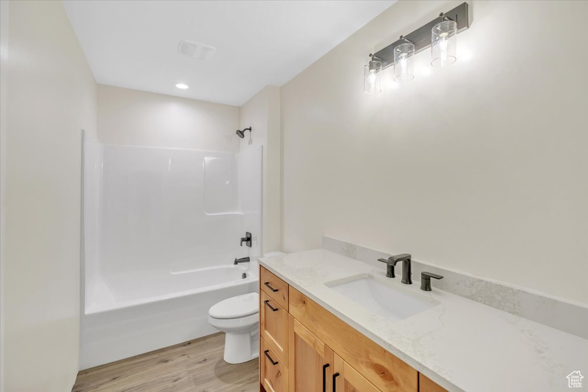 Full bathroom featuring shower / washtub combination, vanity, toilet, and wood-type flooring