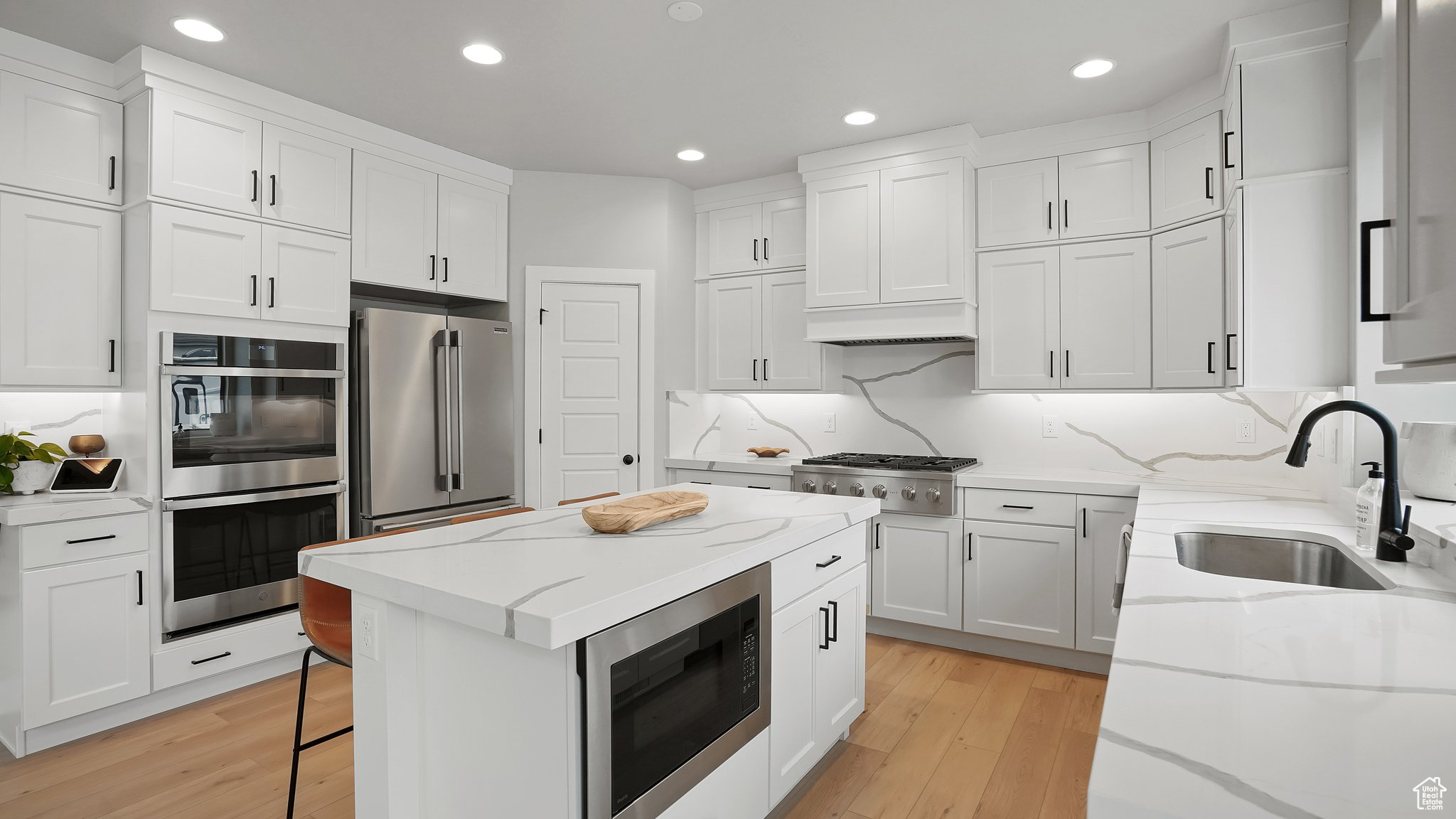 Kitchen featuring stainless steel appliances, sink, light hardwood / wood-style flooring, and backsplash