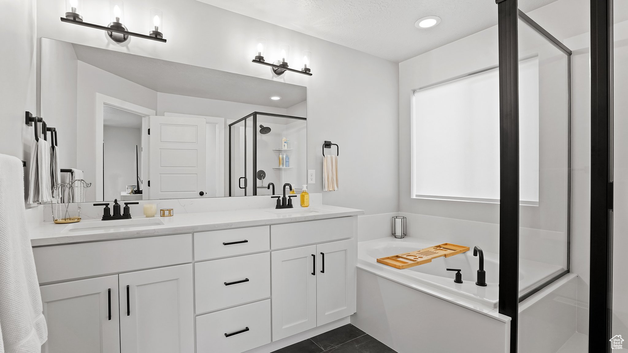 Bathroom featuring dual bowl vanity, tile flooring, and shower with separate bathtub