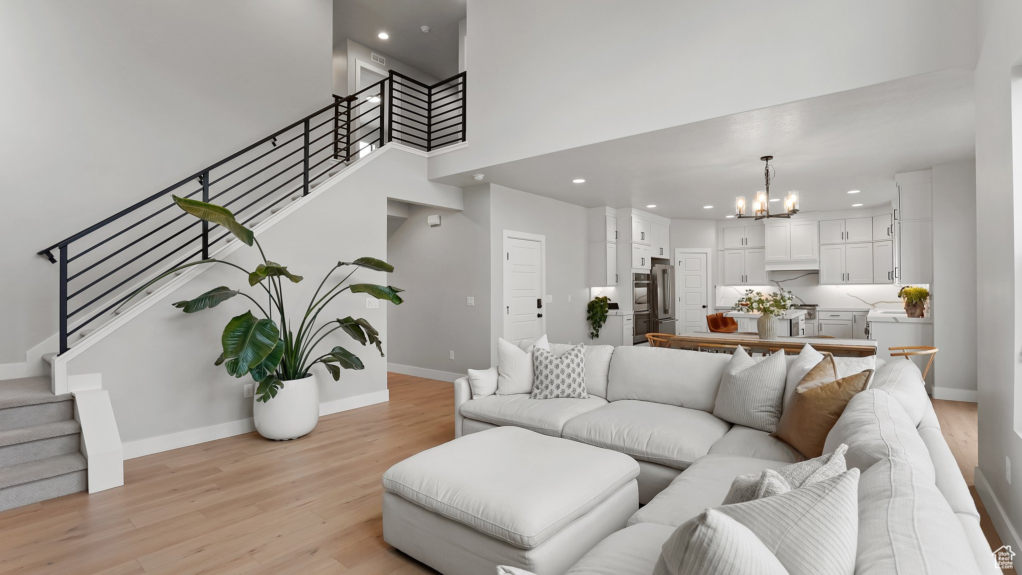 Living room with a notable chandelier, a high ceiling, and light hardwood / wood-style flooring