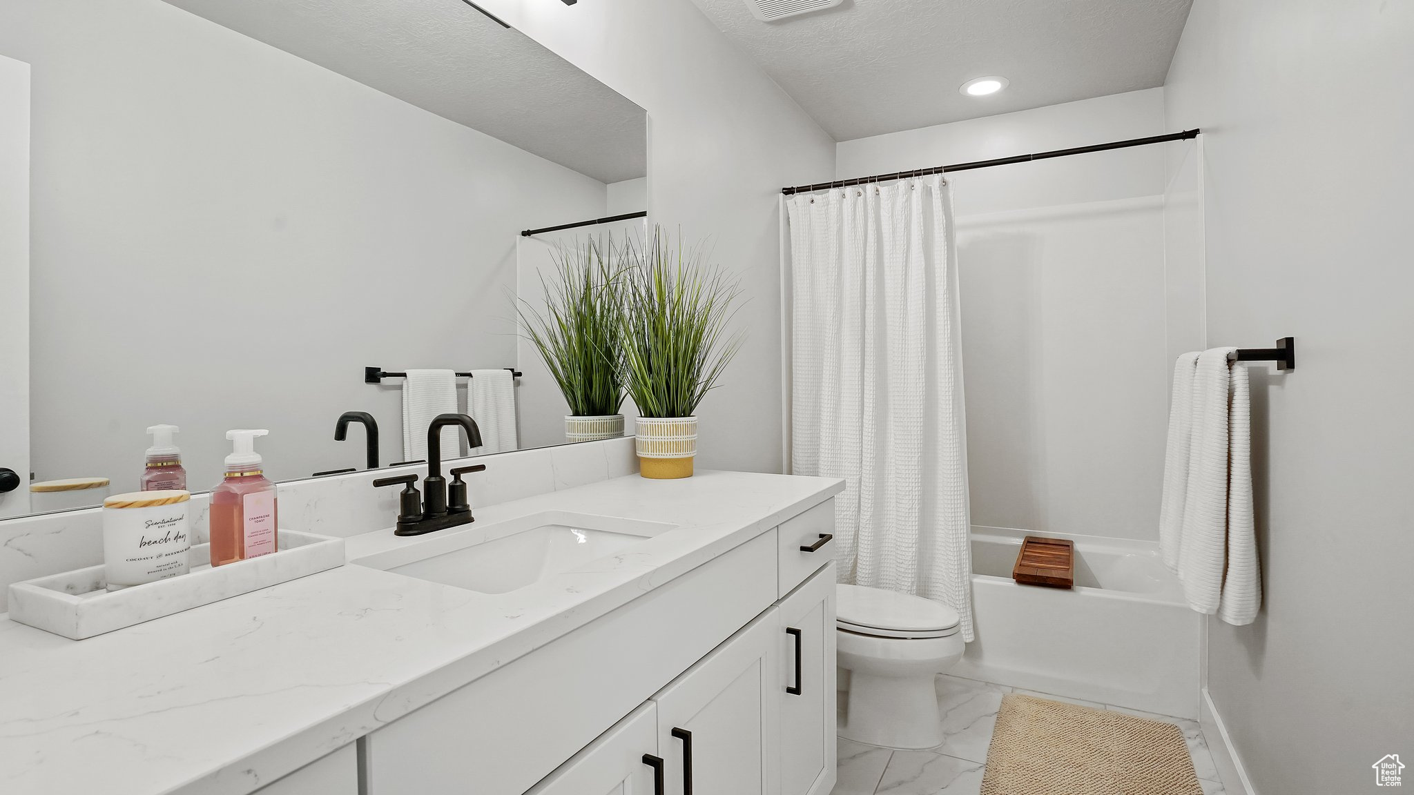 Full bathroom with tile flooring, shower / bath combo, toilet, and large vanity