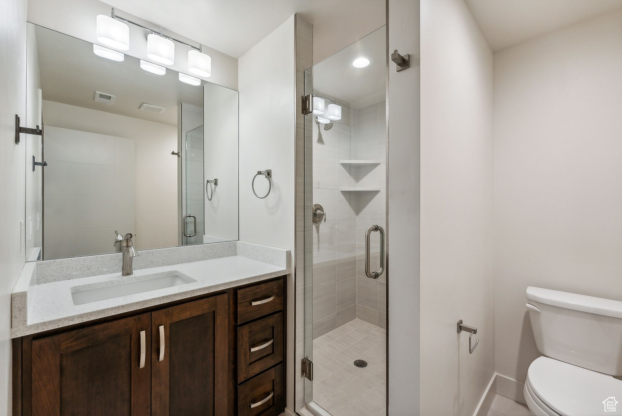Bathroom featuring vanity, toilet, and a shower with shower door
