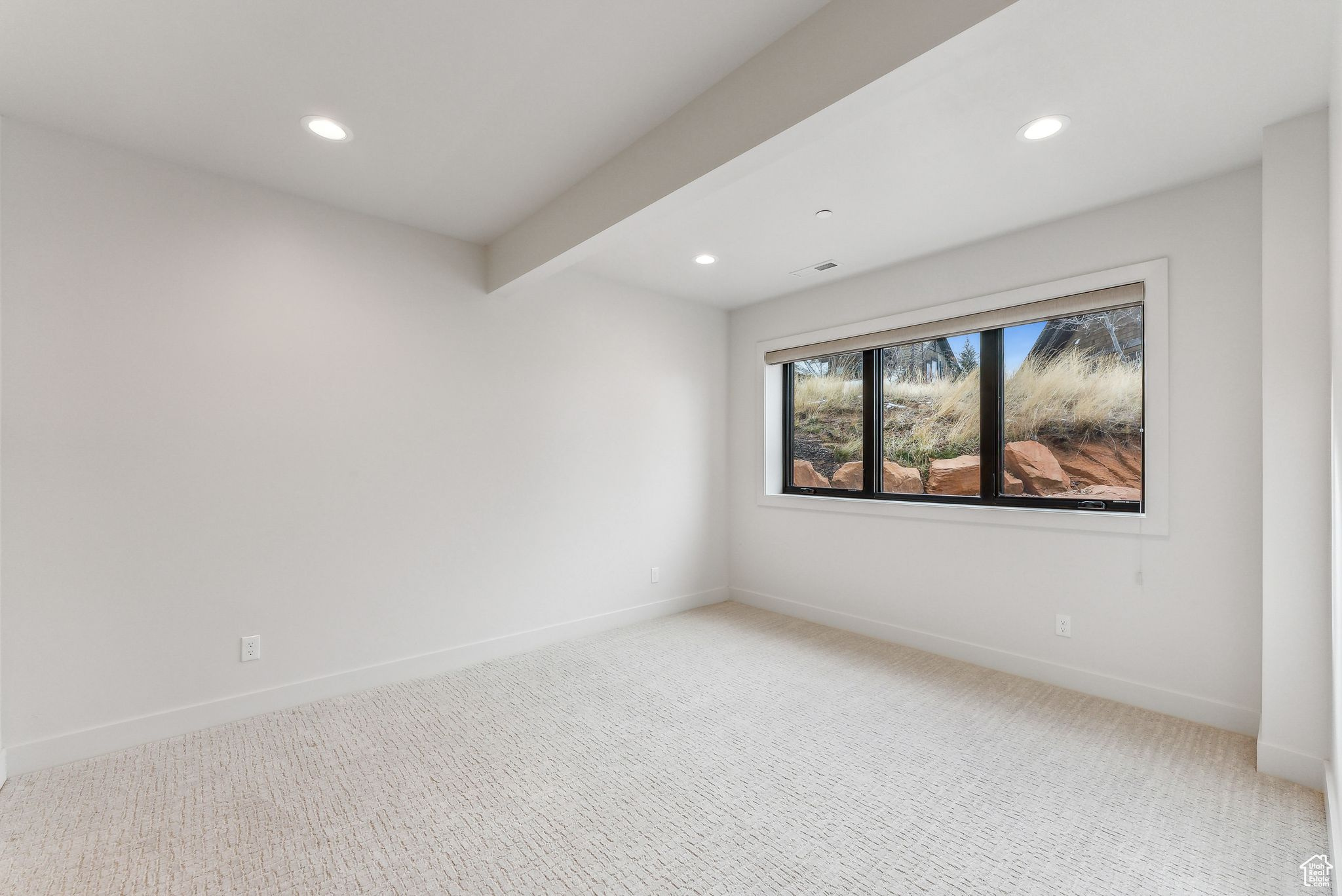 Carpeted spare room featuring beamed ceiling