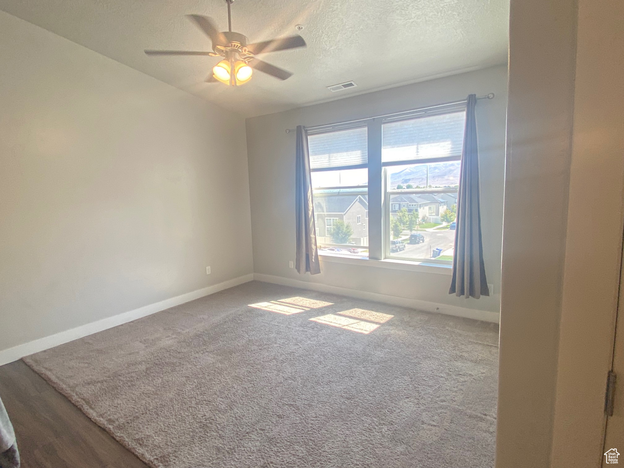 Carpeted empty room featuring ceiling fan and a textured ceiling