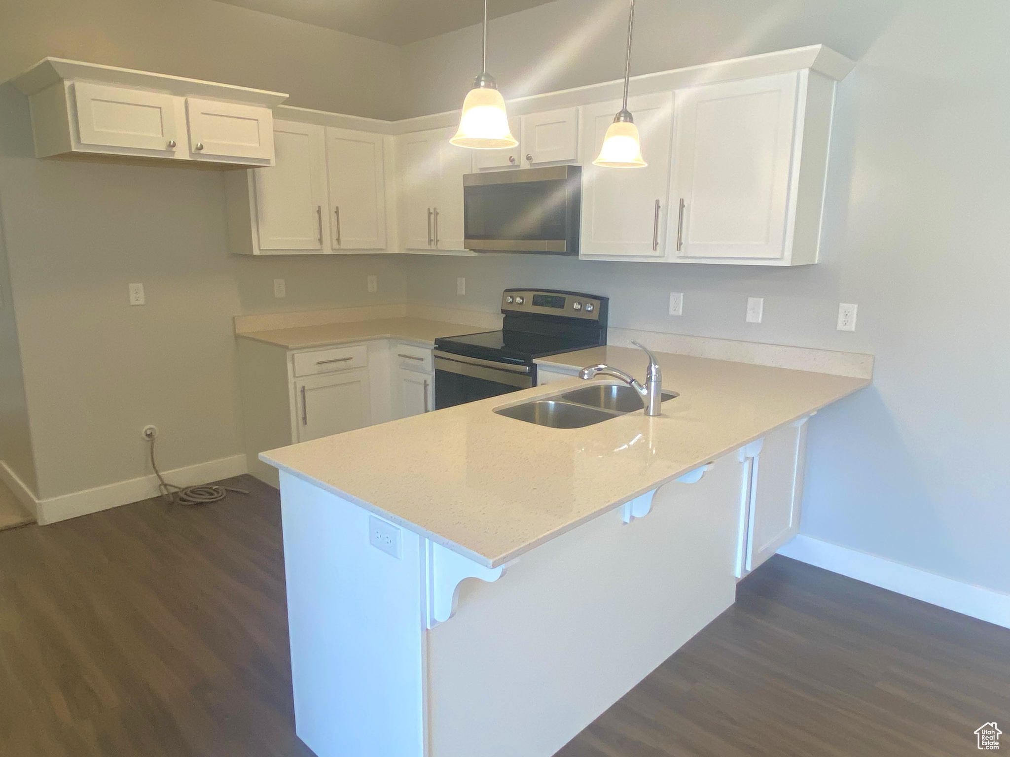 Kitchen with hanging light fixtures, stainless steel appliances, kitchen peninsula, and sink