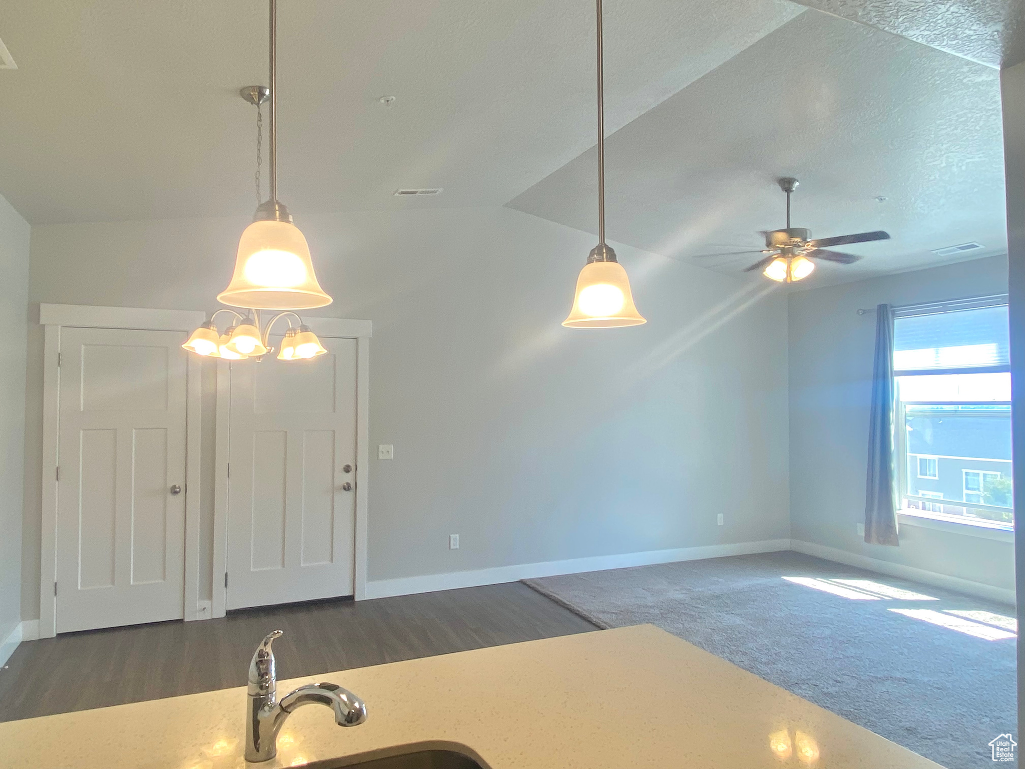 Interior space with vaulted ceiling, ceiling fan with notable chandelier, and carpet floors