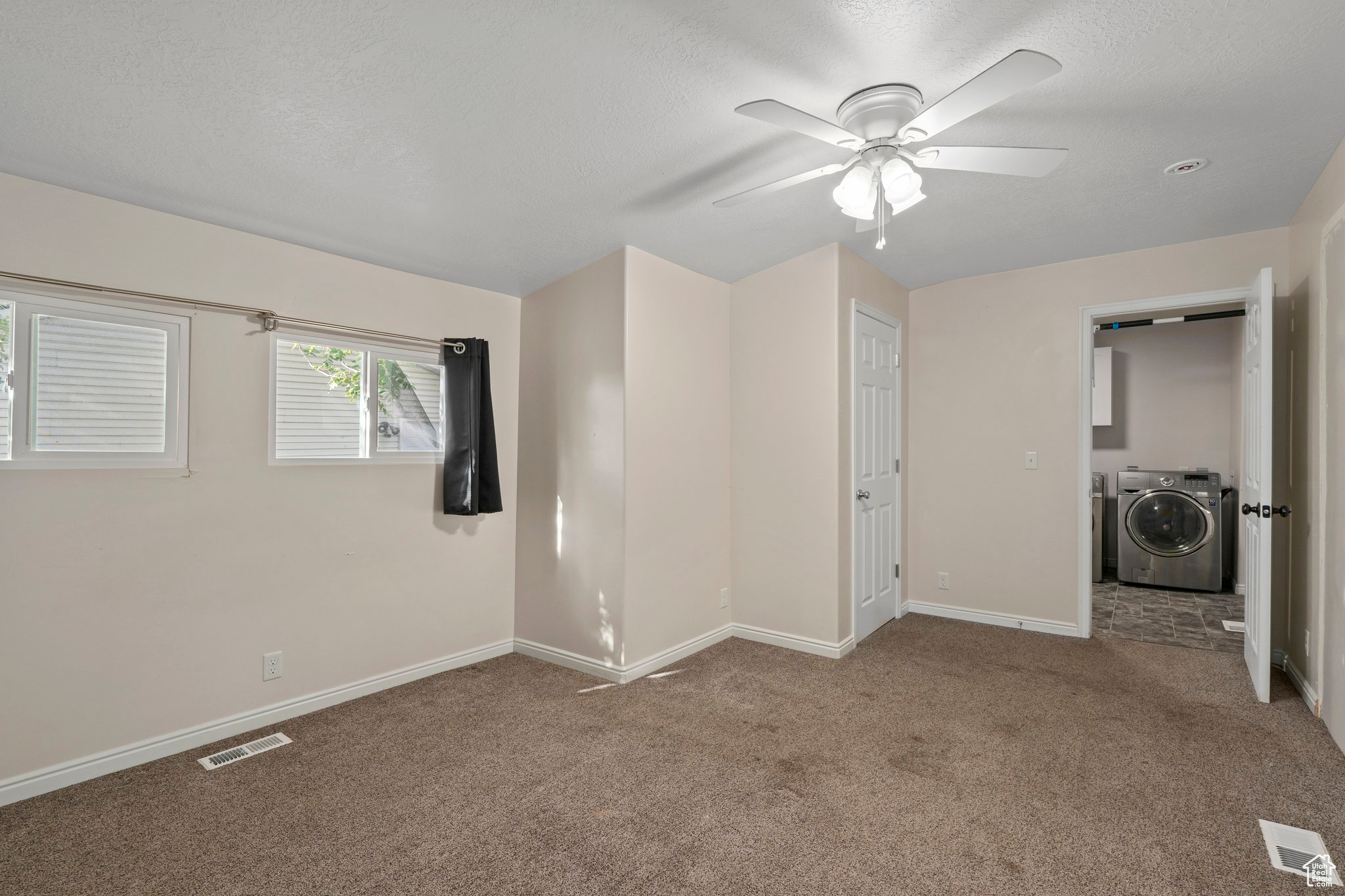 Unfurnished bedroom with a closet, separate washer and dryer, ceiling fan, and carpet floors