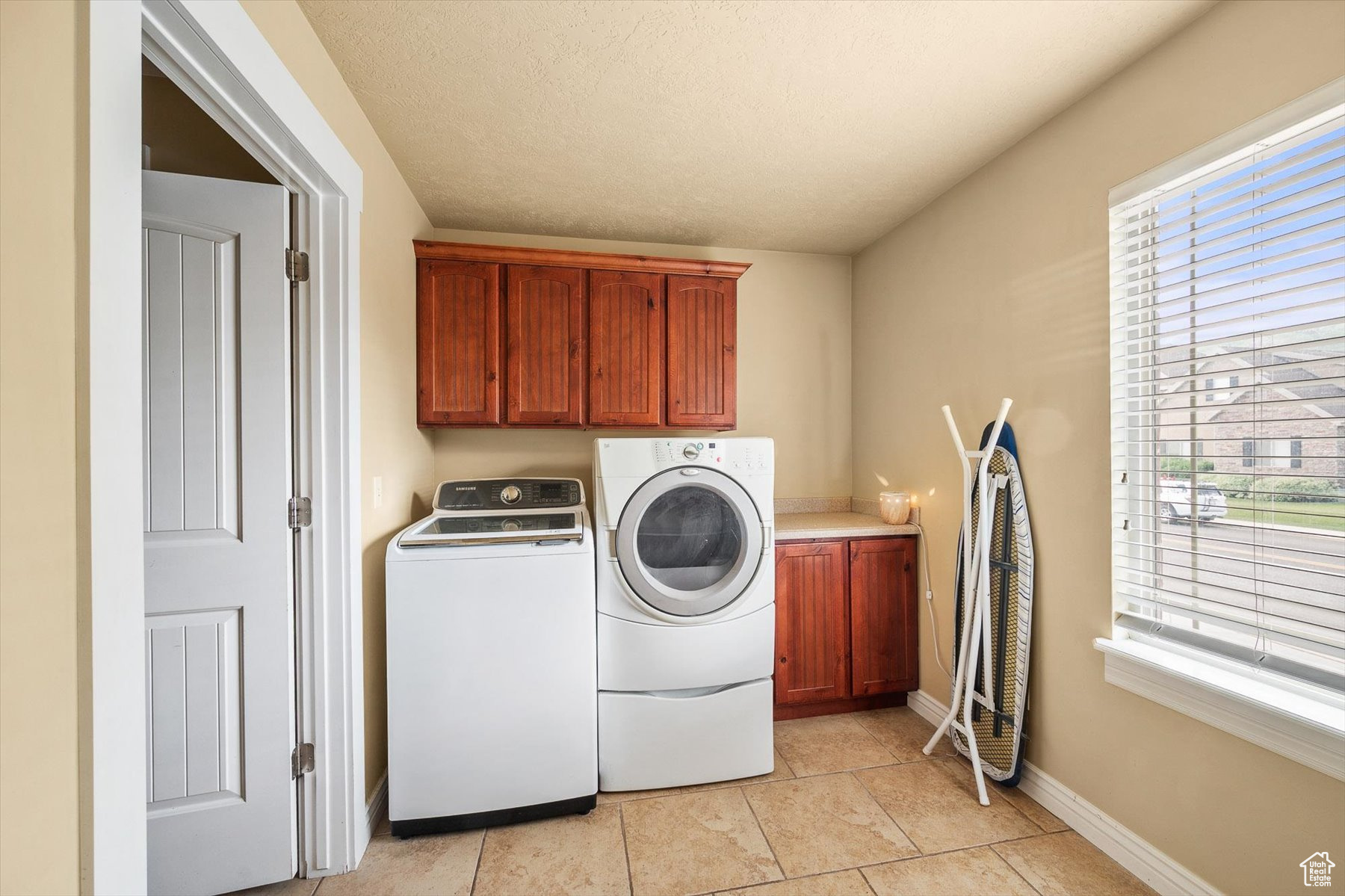 Washroom featuring cabinets, independent washer and dryer, and light tile floors