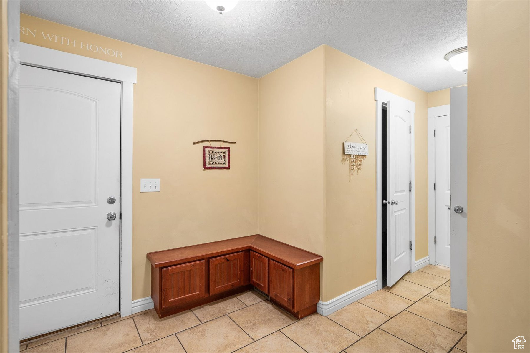 Garage entrance foyer mud room 1/2 bath and aundry with a textured ceiling and light tile flooring