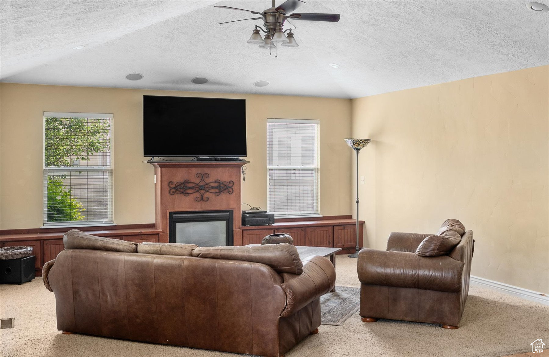 Carpeted living room with ceiling fan and a textured ceiling