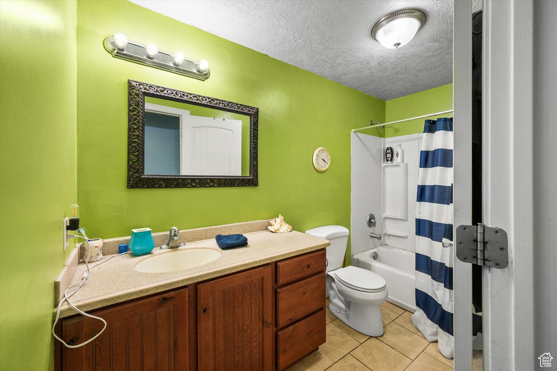 Full bathroom featuring tile flooring, shower / tub combo, a textured ceiling, toilet, and vanity