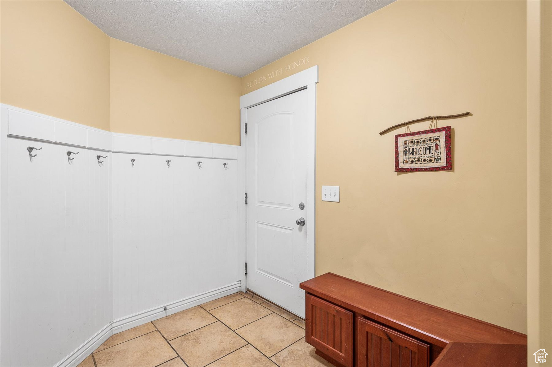 Doorway to outside with light tile flooring and a textured ceiling