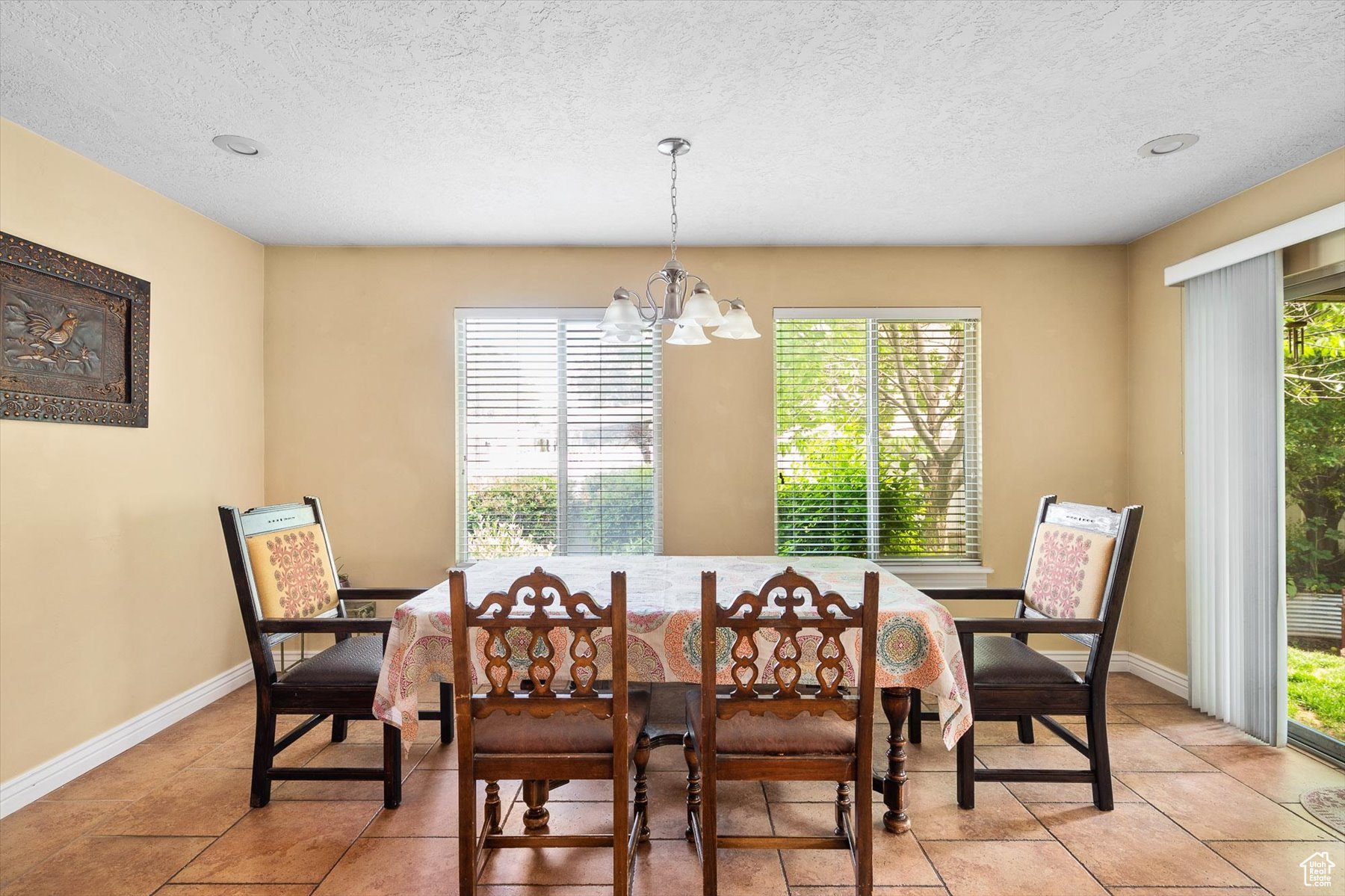 Dining room featuring a textured ceiling, light tile floors, and an inviting chandelier