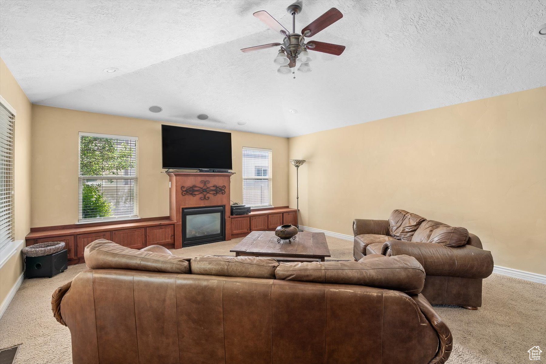 Living room featuring ceiling fan, a textured ceiling, and light colored carpet