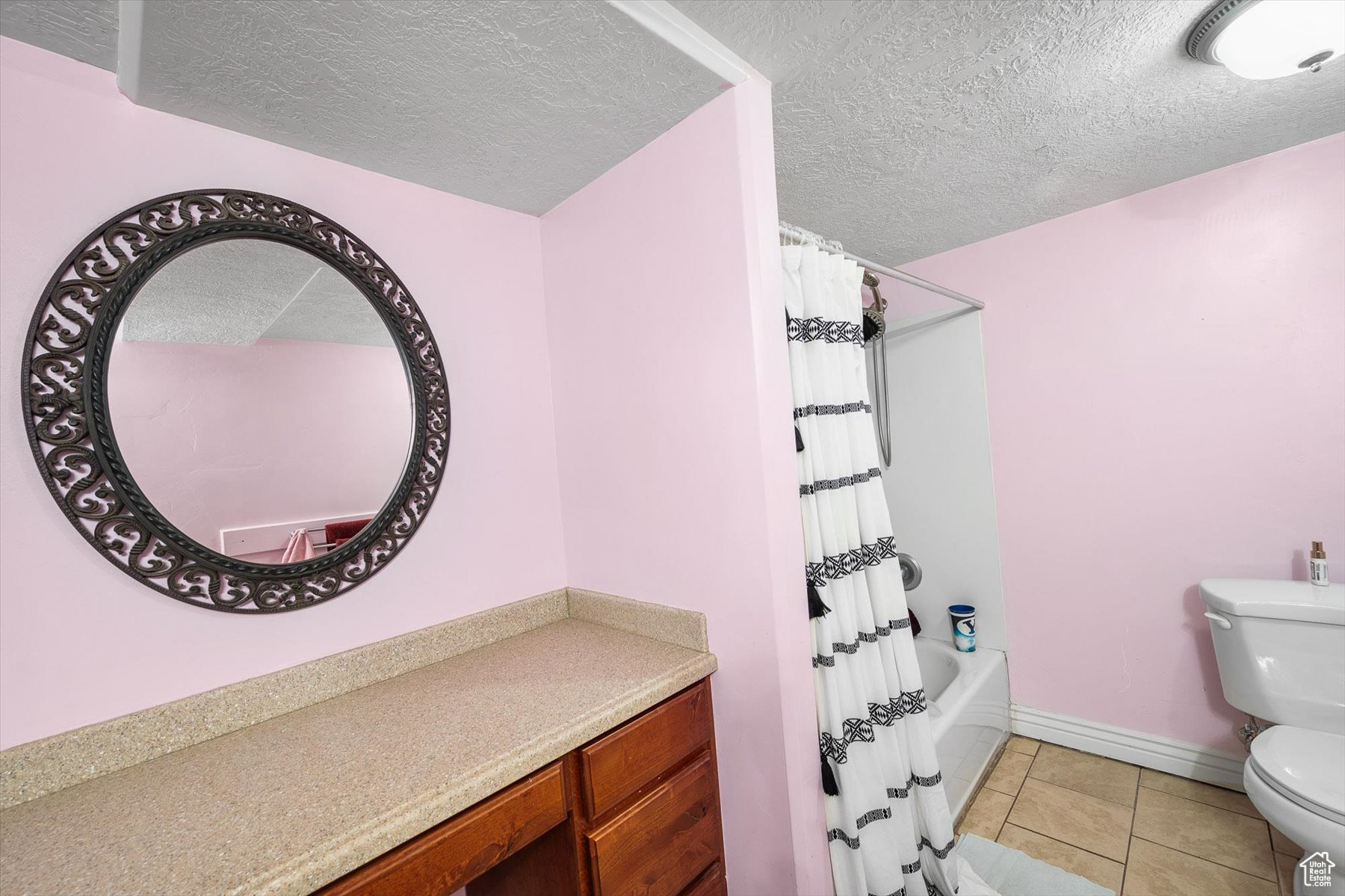 Full bathroom with tile floors, a textured ceiling, and toilet