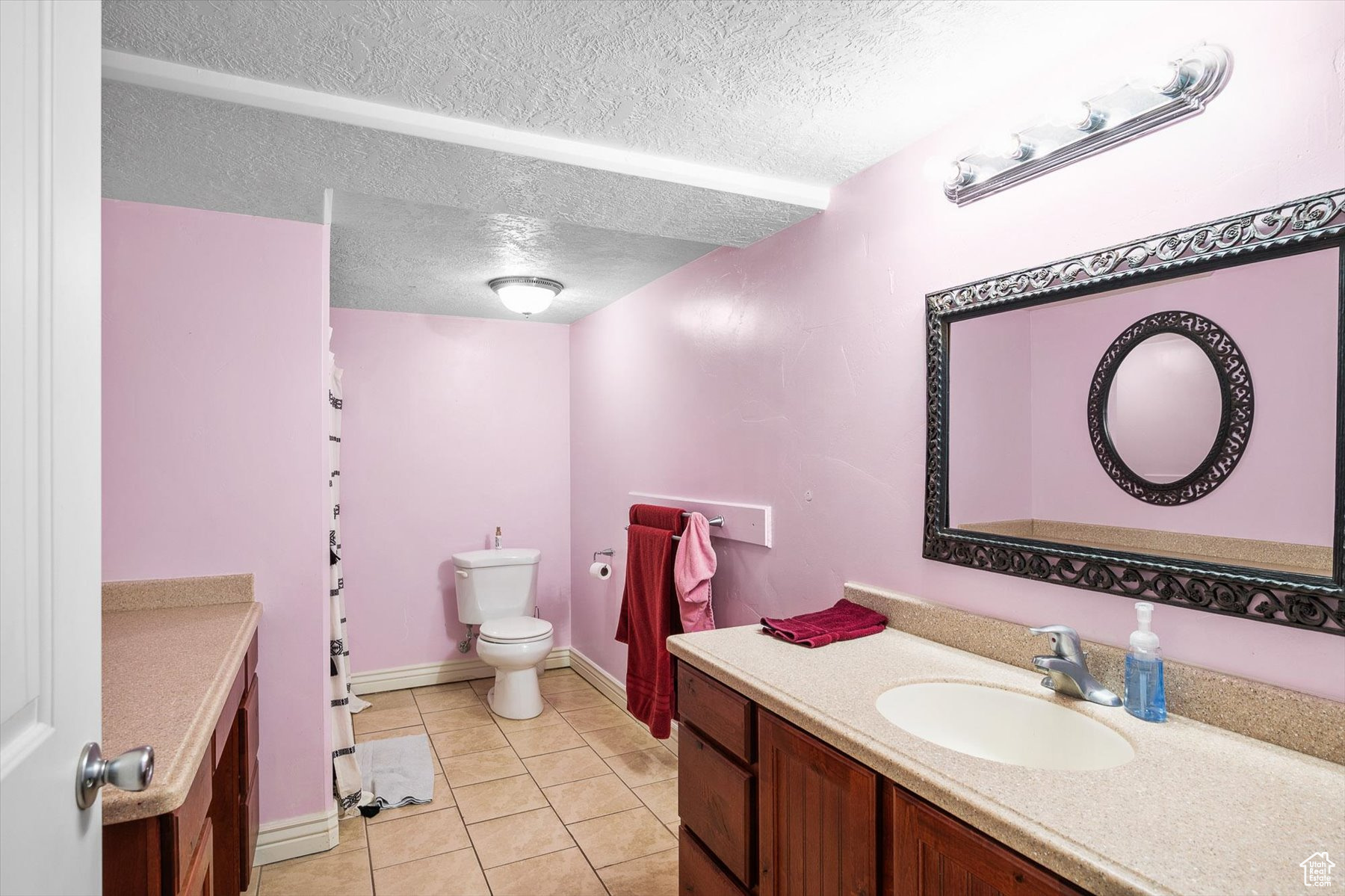 Bathroom with tile floors, a textured ceiling, vanity, and toilet