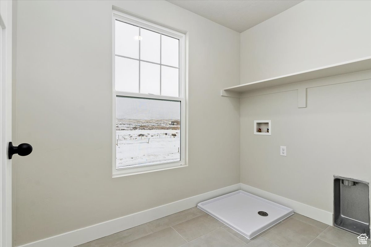 Clothes washing area with tile floors, washer hookup, and a wealth of natural light