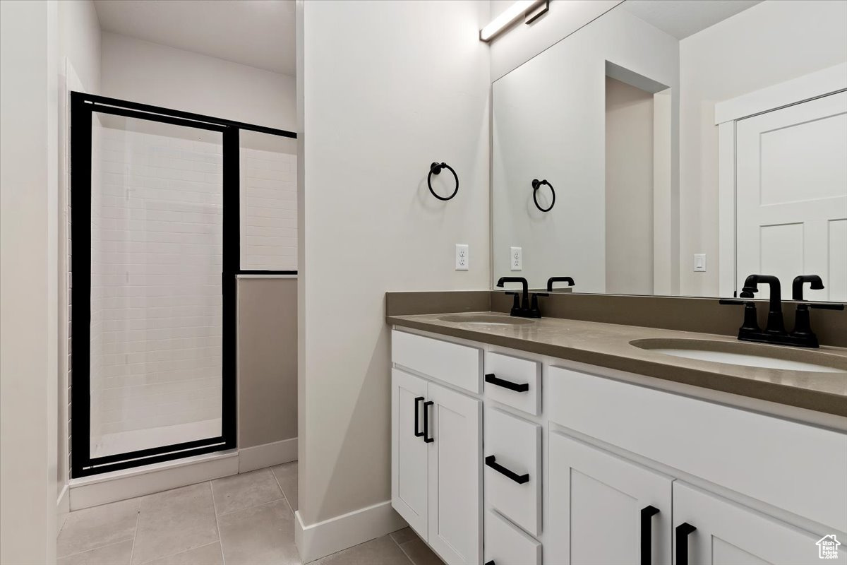 Bathroom featuring walk in shower, double sink, oversized vanity, and tile floors