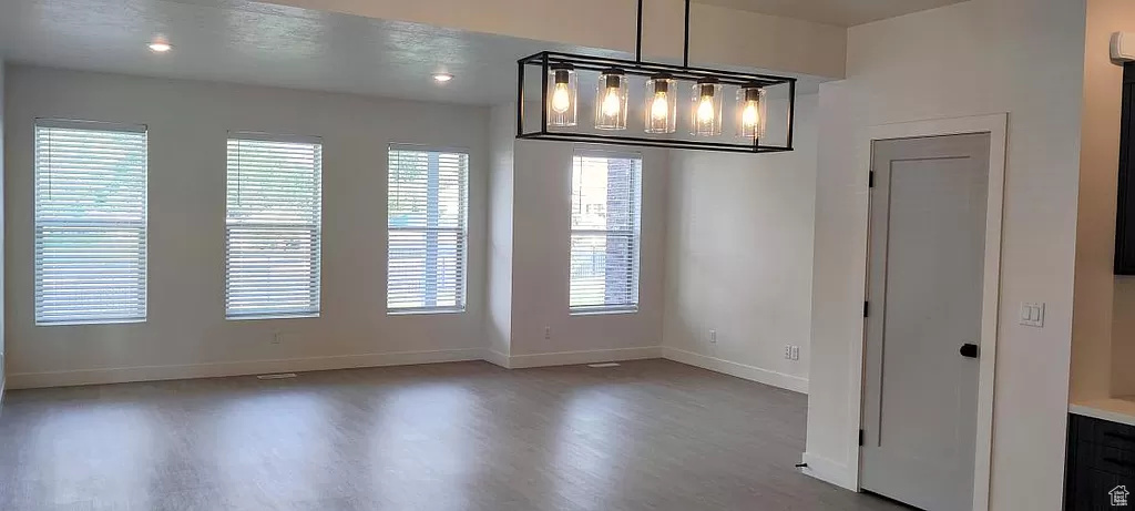 Unfurnished dining area featuring a notable chandelier, hardwood / wood-style floors, and plenty of natural light