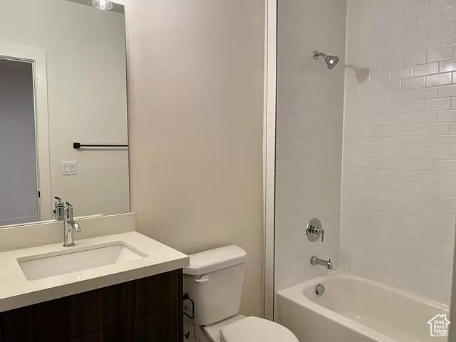 Full bathroom featuring tiled shower / bath, vanity, and toilet