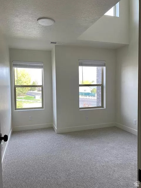 Carpeted empty room with a textured ceiling