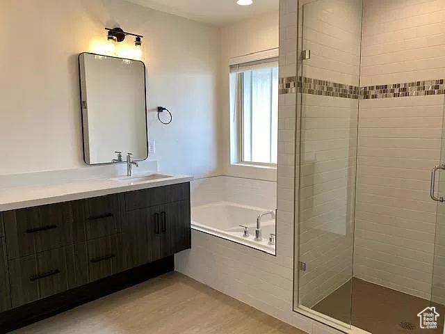 Bathroom with shower with separate bathtub, hardwood / wood-style floors, and large vanity