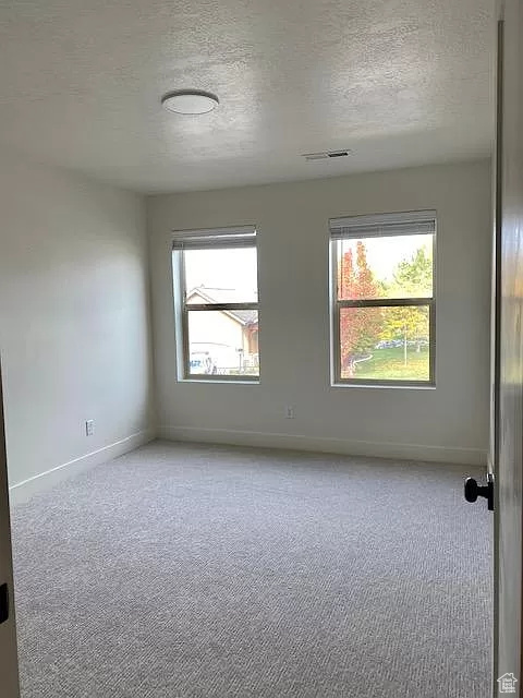 Carpeted empty room featuring a textured ceiling