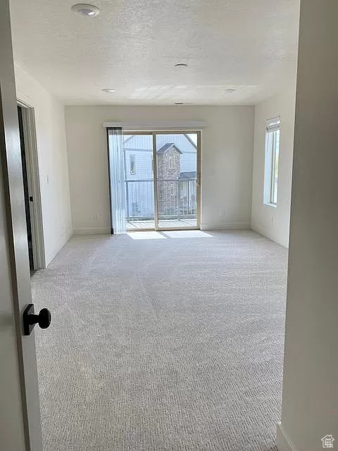 Empty room featuring light carpet and a textured ceiling