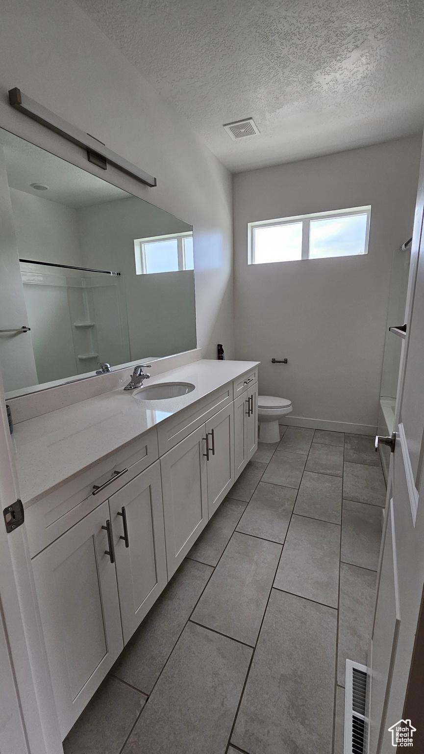 Bathroom with vanity with extensive cabinet space and toilet