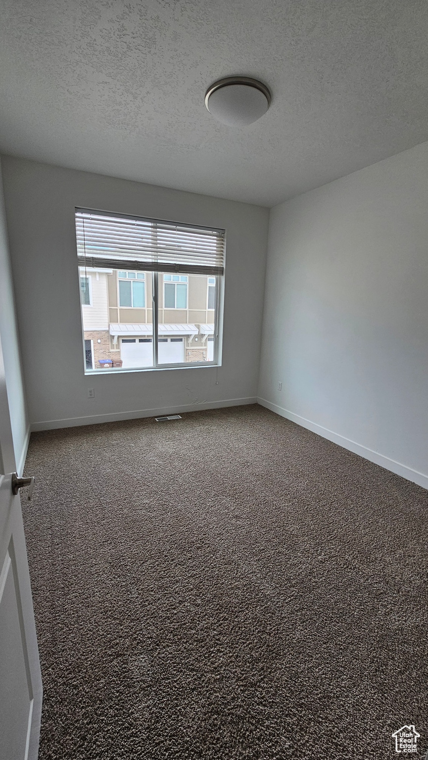 Carpeted spare room featuring a textured ceiling